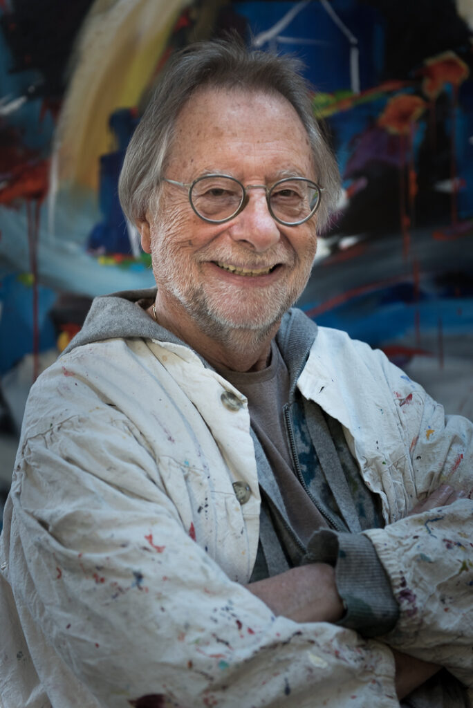 Artiste souriant portant un blouson plein de peinture, Salle d’exposition Martres Tolosane.
