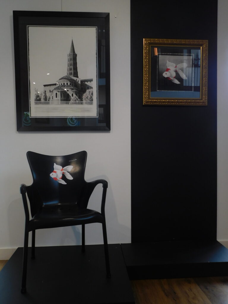 Une chaise noire avec un poisson rouge, exposée à la Salle d’exposition Martres Tolosane.