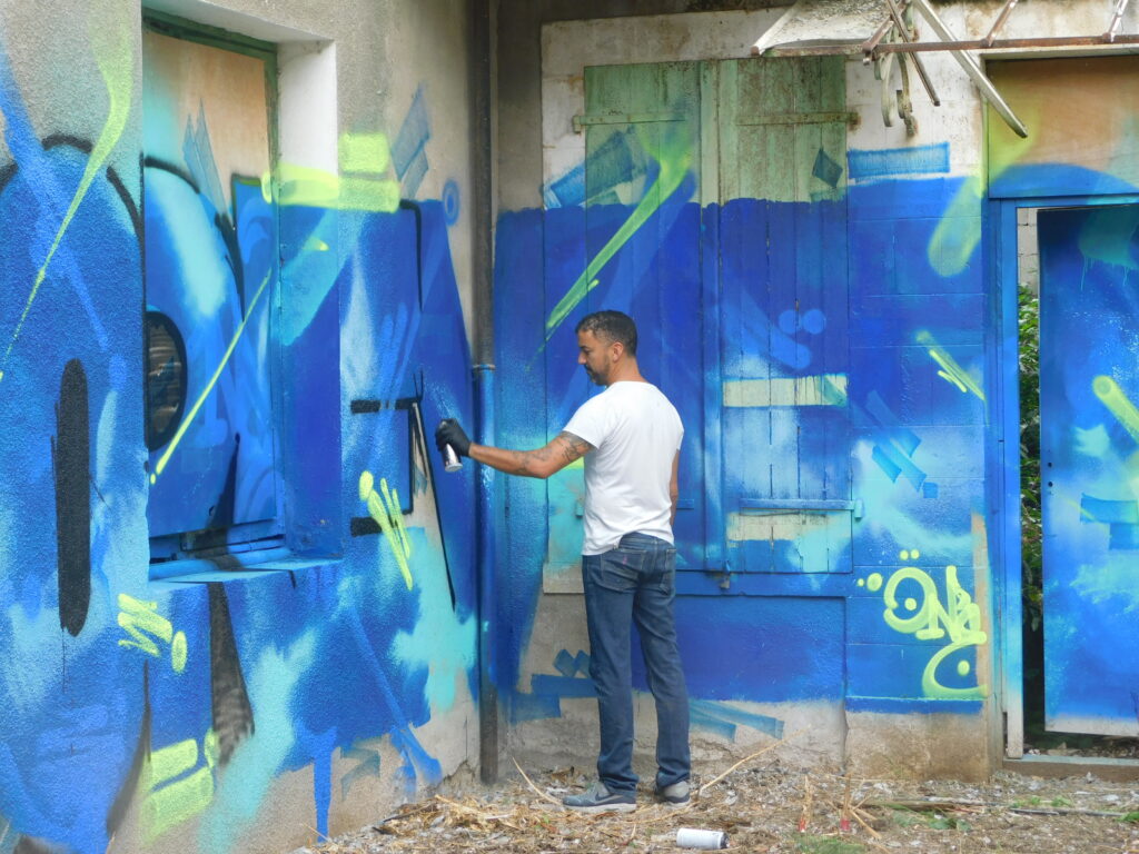 Artiste peignant un mur au Grand Presbytère, Salle d’exposition Martres Tolosane.