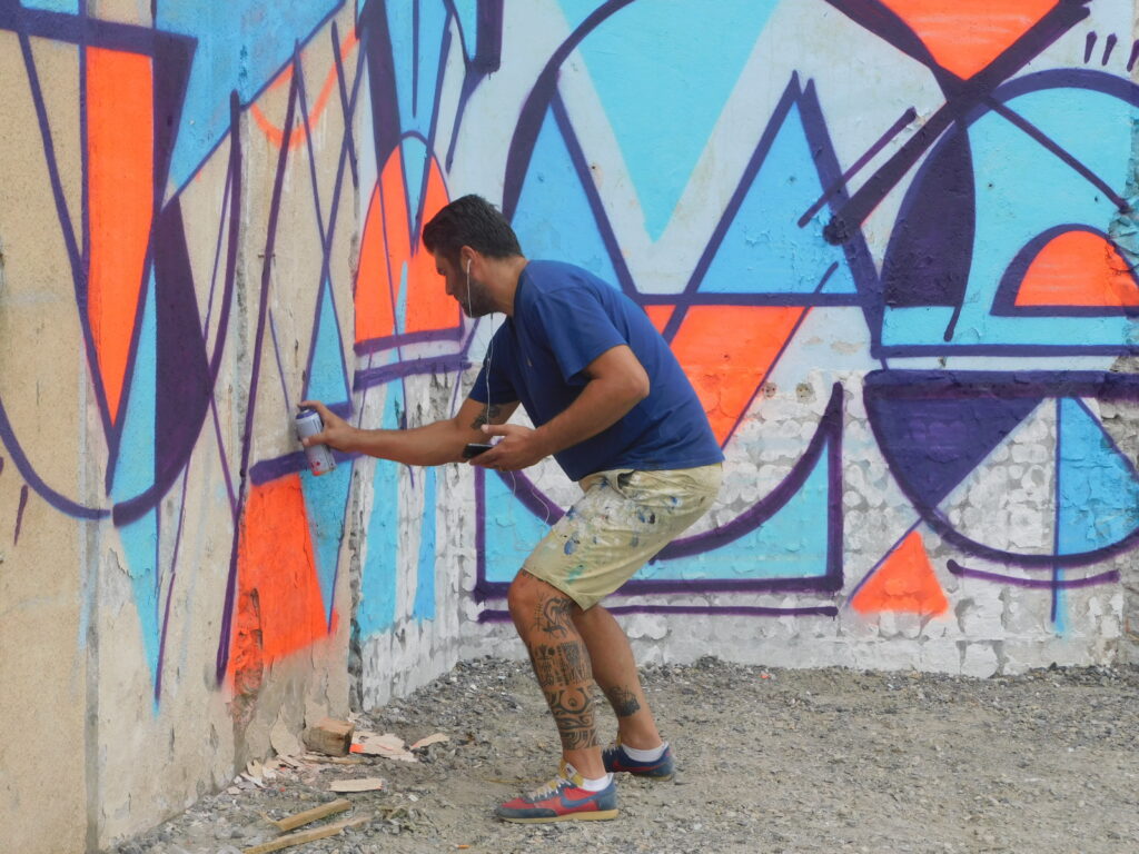 Homme peignant un mur avec des motifs colorés au Grand Presbytère.