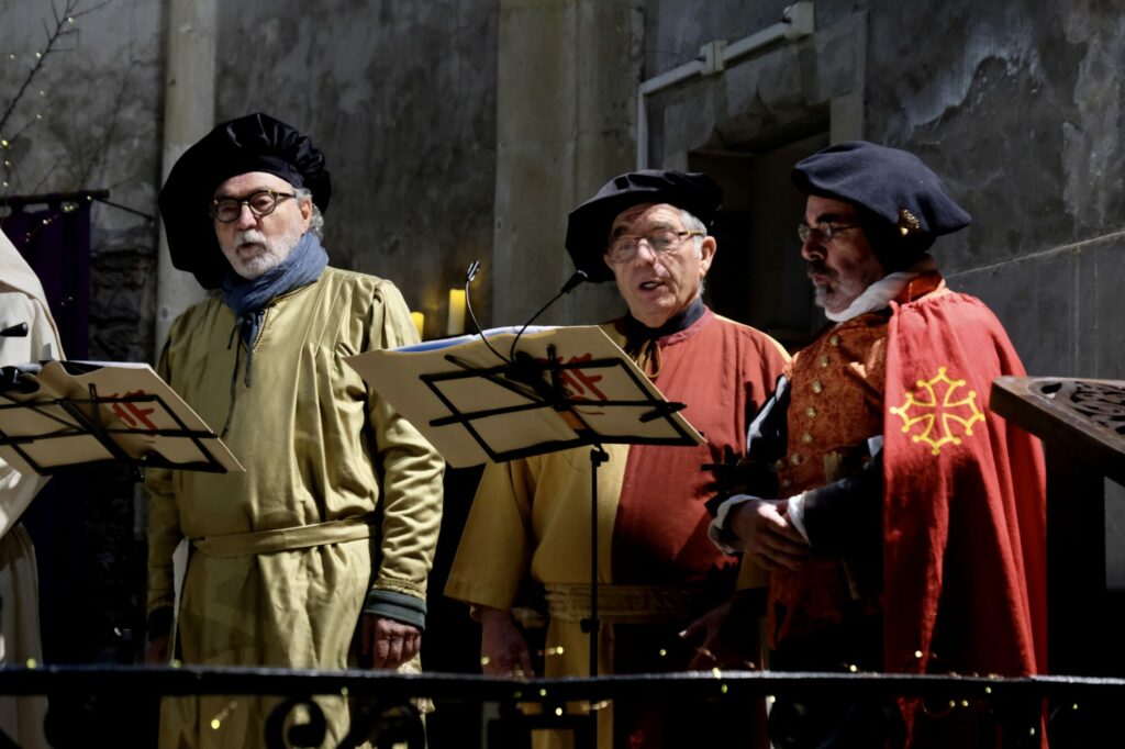 Trois hommes costumés chantent au Grand Presbytère Martres Tolosane.